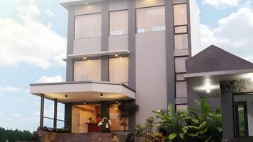 A modern two-story building with a flat roof, large windows, and a covered entrance area.