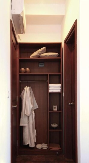 A narrow walk-in closet with shelves, a hanging rod, and a shoe rack.