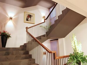A staircase with wooden handrails and a light fixture on the wall.