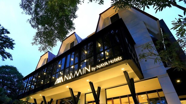 A modern hotel with a prominent 'NAYA Hotels' sign, featuring a unique architectural design with angular lines and large windows. - Hotel Namin (Bandung)
