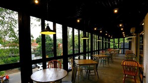 A restaurant with large windows, wooden tables, and chairs. - Hotel Namin (Bandung)
