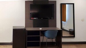A hotel room with a desk, chair, TV, and a large mirror. - Americas Best Value Inn Downtown (Los Angeles)
