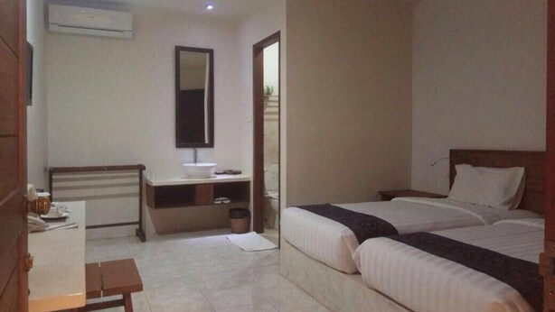 Una habitación de hotel con dos camas, un escritorio, un espejo y un equipo de aire acondicionado.