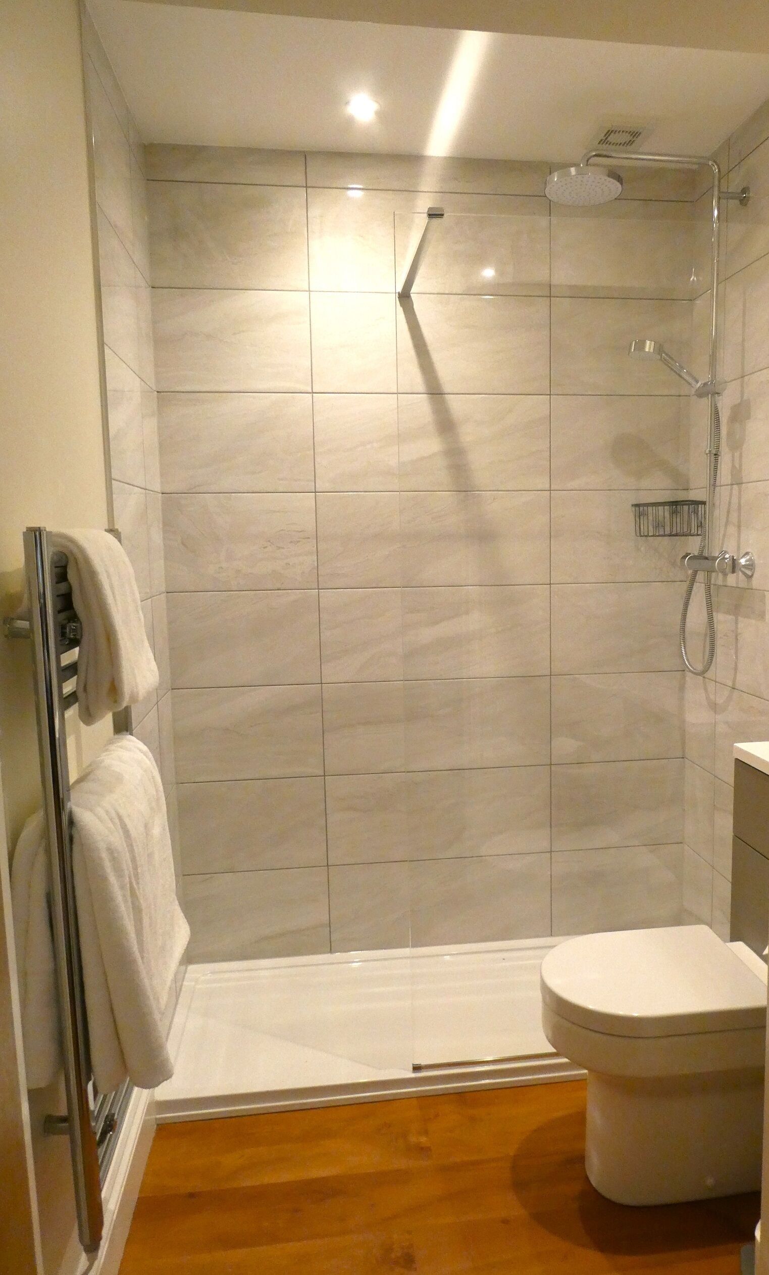 A modern bathroom with a shower, toilet, and a towel rack.