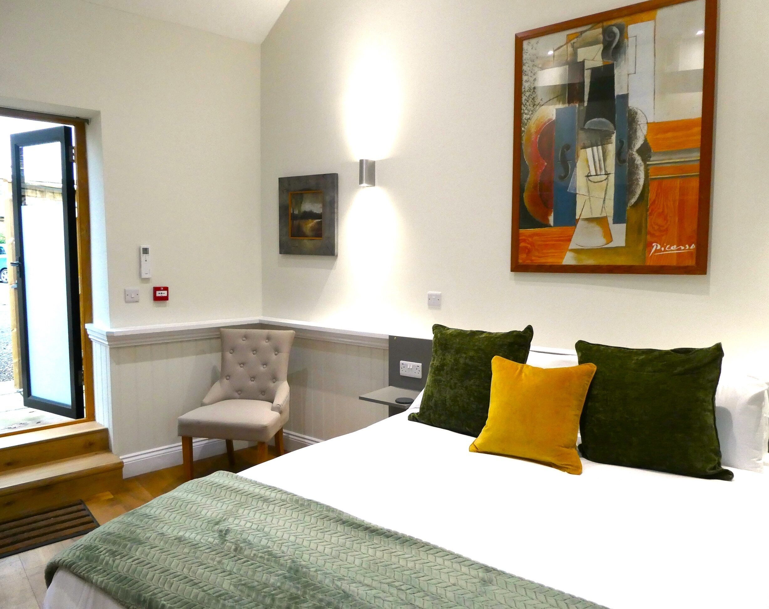 A bedroom with a bed, a chair, a painting, and a lamp.