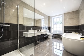 A modern bathroom with a glass-enclosed shower, a freestanding bathtub, and a double sink vanity. - The Frocester (Stonehouse)