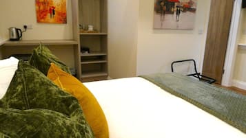 A hotel room with a bed, a wardrobe, and two paintings on the walls.