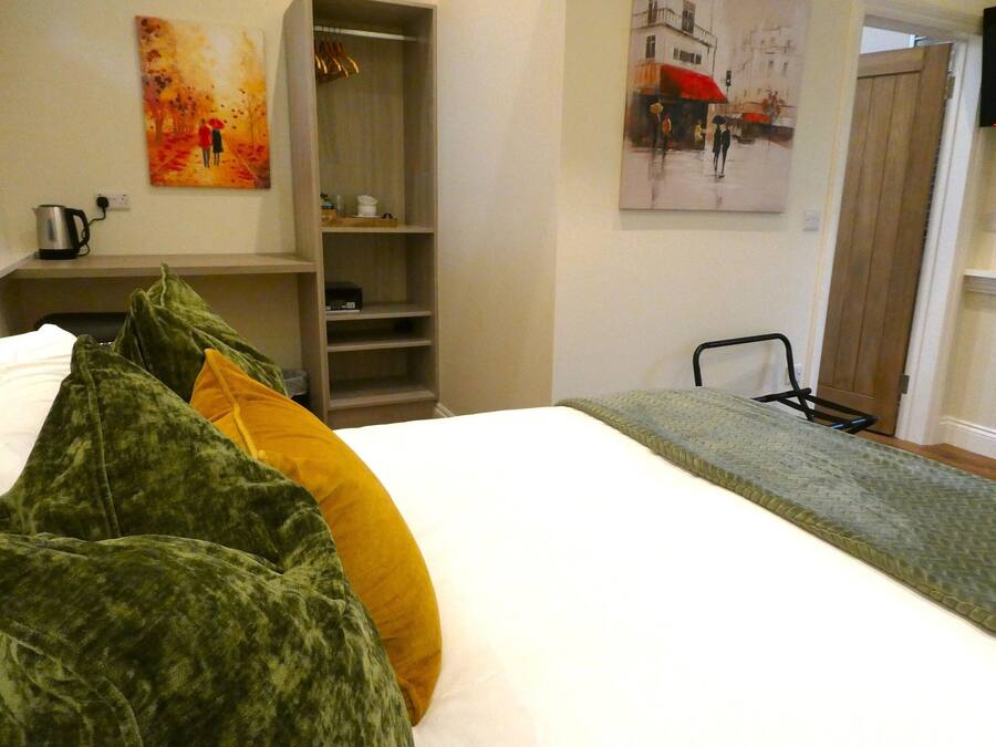 A hotel room with a bed, a wardrobe, and two paintings on the walls.
