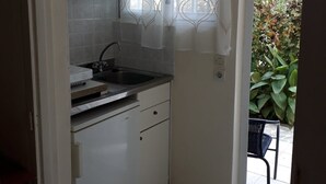 Een kleine keuken met witte kastjes, een roestvrijstalen spoelbak en een betegelde achterwand.