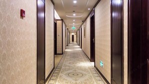 A long, narrow hallway with patterned carpet and wooden doors on both sides. - Vienna Hotel (Shanghai Jinqiao Park Taierzhuang Road Subway Station) (Shanghai)