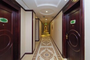 A hotel hallway with ornate carpet, wooden doors, and a ceiling with recessed lighting. - Vienna Hotel (Shanghai Jinqiao Park Taierzhuang Road Subway Station) (Shanghai)