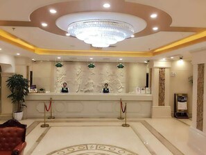 A hotel reception area with a chandelier, a reception desk, and a red carpet leading to the entrance. - Vienna Hotel (Shanghai Jinqiao Park Taierzhuang Road Subway Station) (Shanghai)