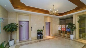 A hotel lobby with three elevators, a chandelier, potted plants, and a reception desk. - Vienna Hotel (Shanghai Jinqiao Park Taierzhuang Road Subway Station) (Shanghai)