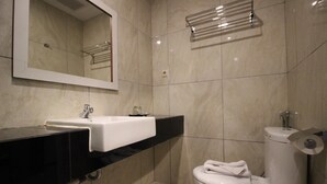 Une salle de bain avec un lavabo blanc, des toilettes et un miroir au-dessus du lavabo.