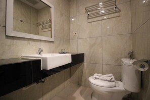 Een badkamer met een wit wastafel, toilet en spiegel boven de wastafel.