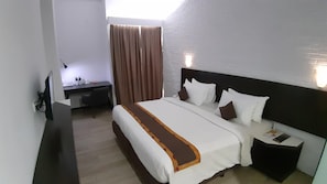Een hotelkamer met een bed, nachtkastje en een bureau met stoel.