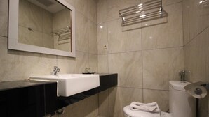 A modern bathroom with a white sink, black countertop, and a toilet with a towel on it. - Xtra Bengkulu Managed by Dafam (Bengkulu)