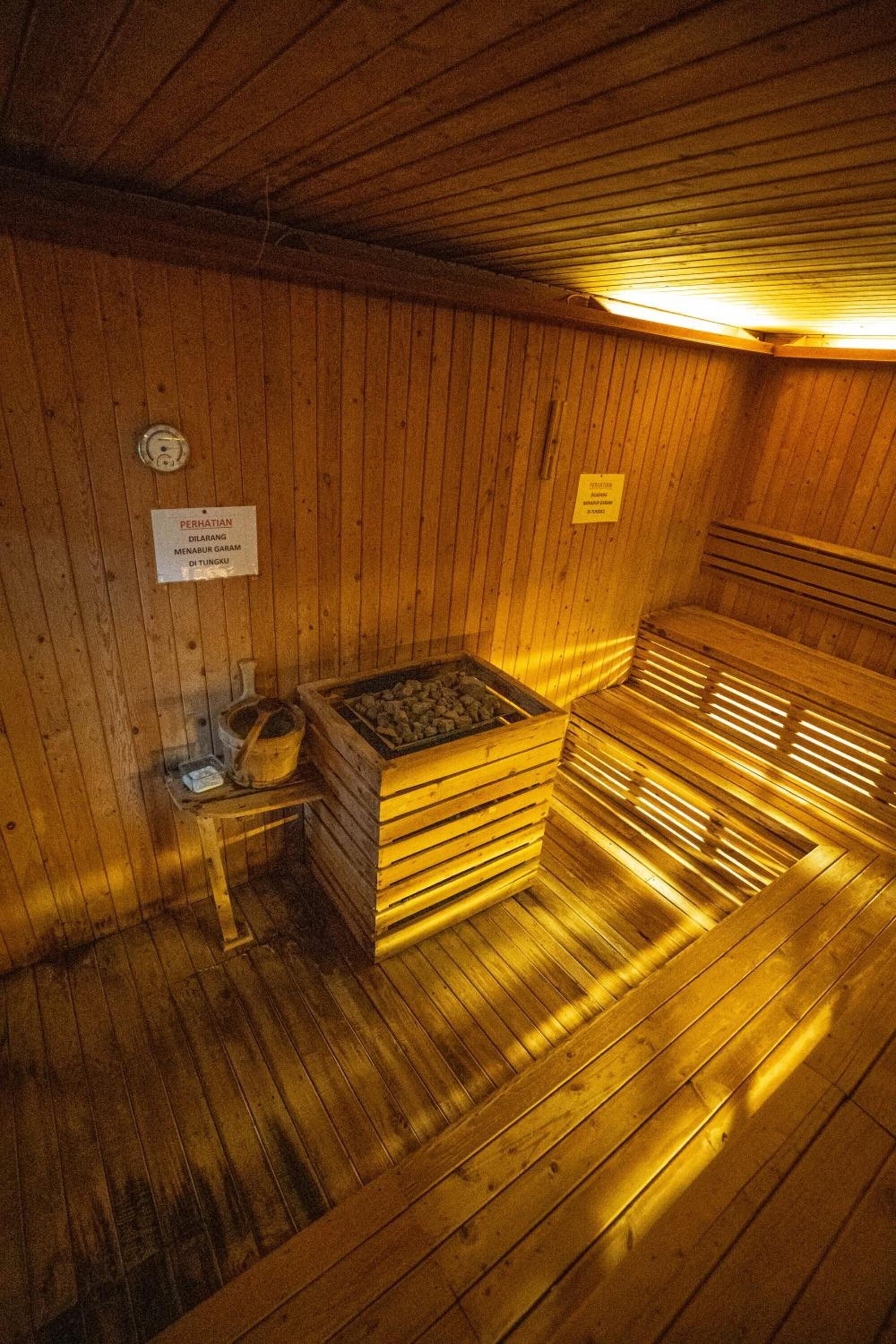 A wooden sauna with benches and a stone basin.