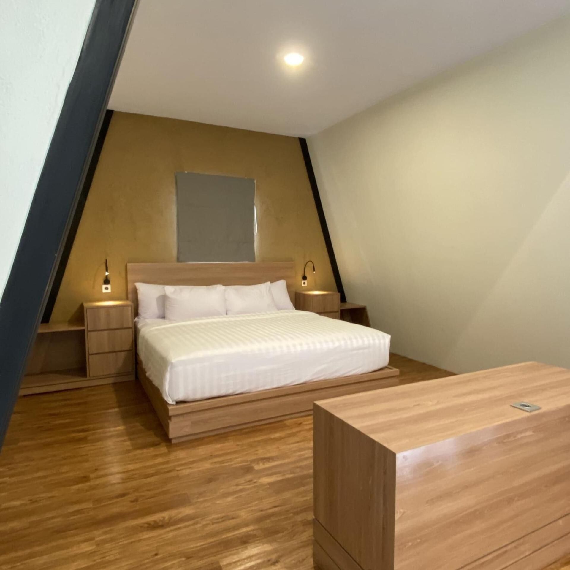 A bedroom with a bed, bedside tables, a nightstand, a wooden dresser, and a ceiling light.