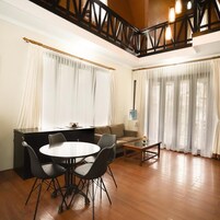 Un comedor con una mesa redonda y sillas, un sofá, una mesa de centro y una escalera con barandillas de madera.