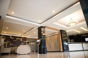 A modern lobby with a reception desk, seating area, and a chandelier.