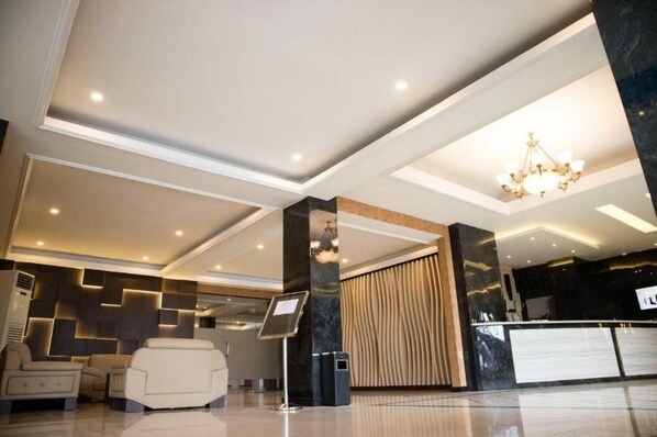A modern lobby with a reception desk, seating area, and a chandelier. - Karlita Hotel Tegal (Tegal)