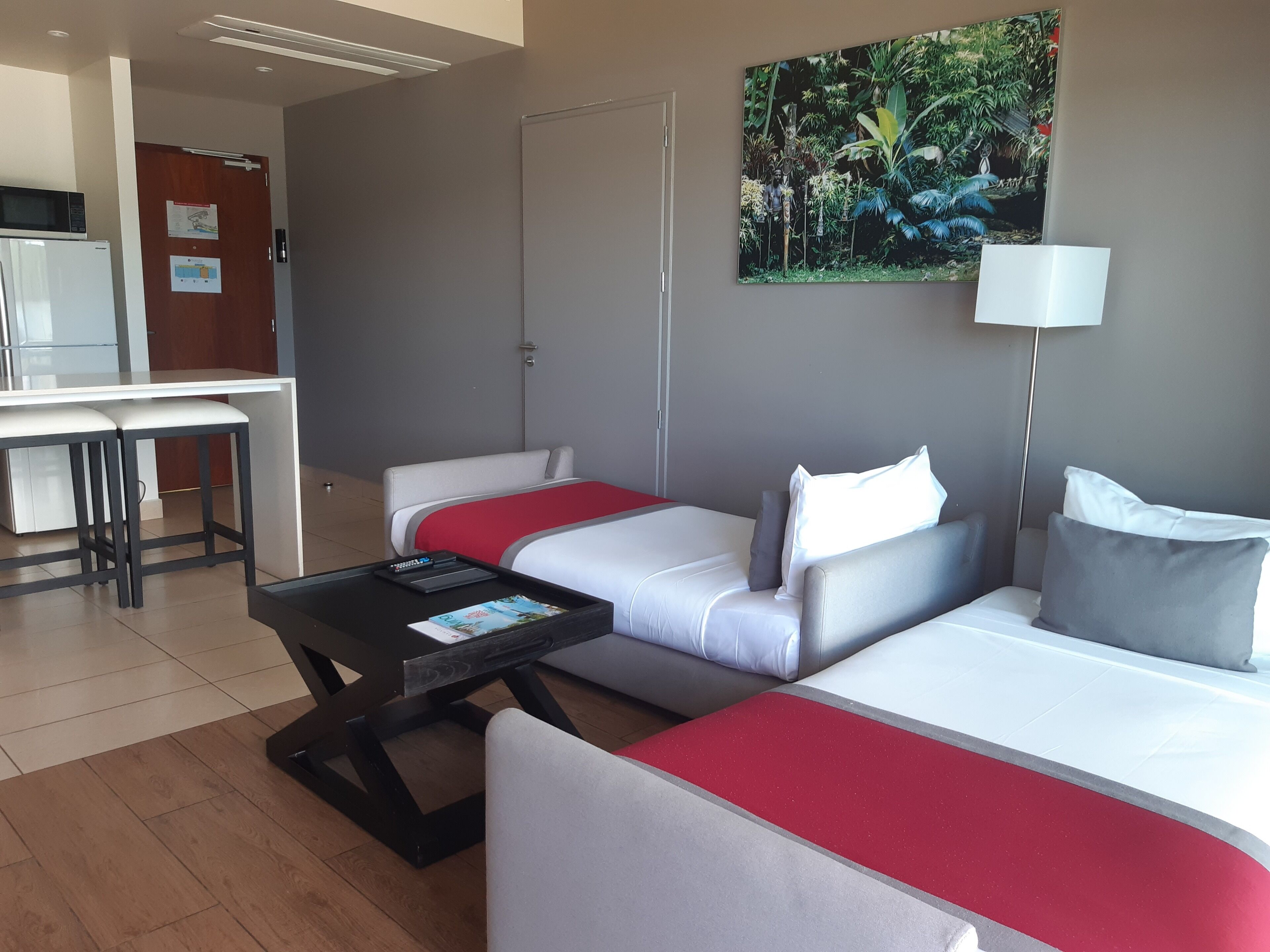 Habitación de hotel con cama, escritorio y silla. Hay un cuadro en la pared y una lámpara.