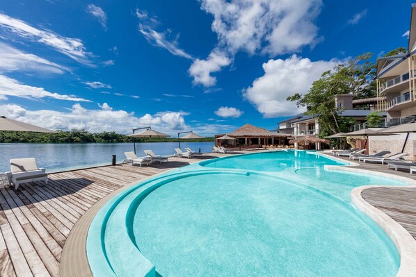 Un espace piscine avec des chaises longues et vue sur l’eau.