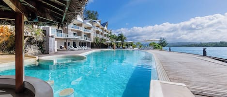 Ein Hotelpool mit Holzterrasse und Blick auf das Meer.