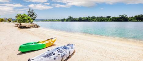 A beach with kayaks and a small island with trees.