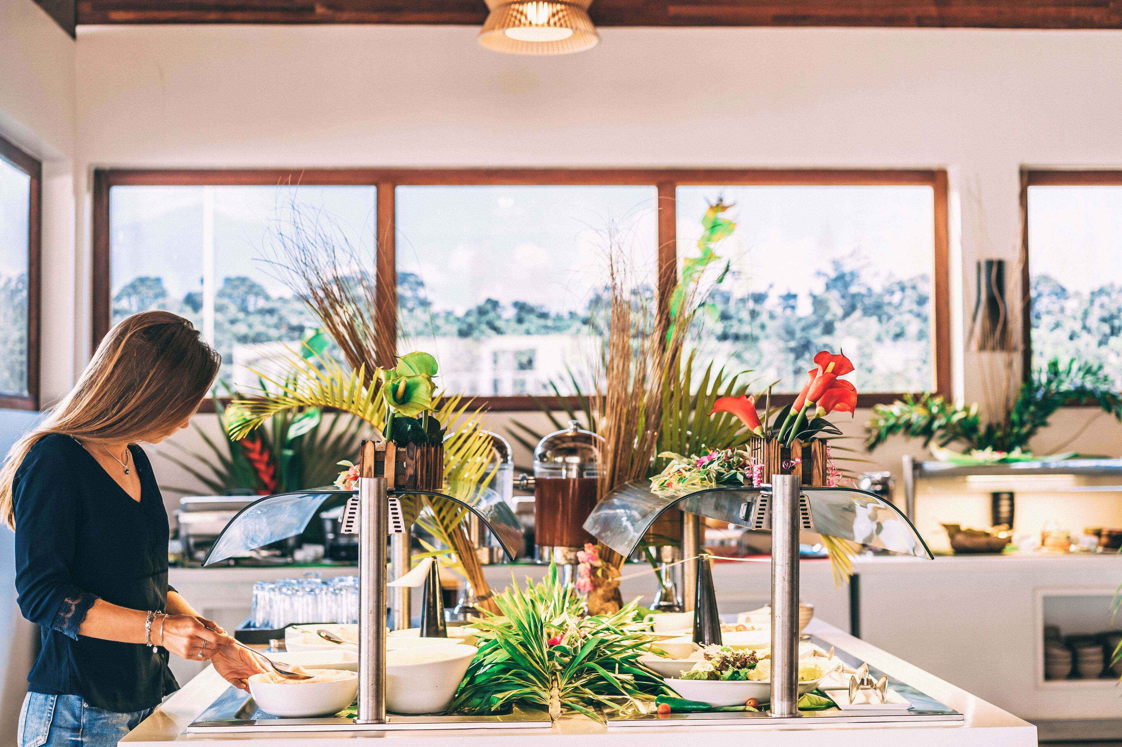 A buffet setup with a variety of dishes and a person serving food.