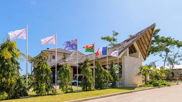 A building with multiple flags, a thatched roof, and a stone facade.