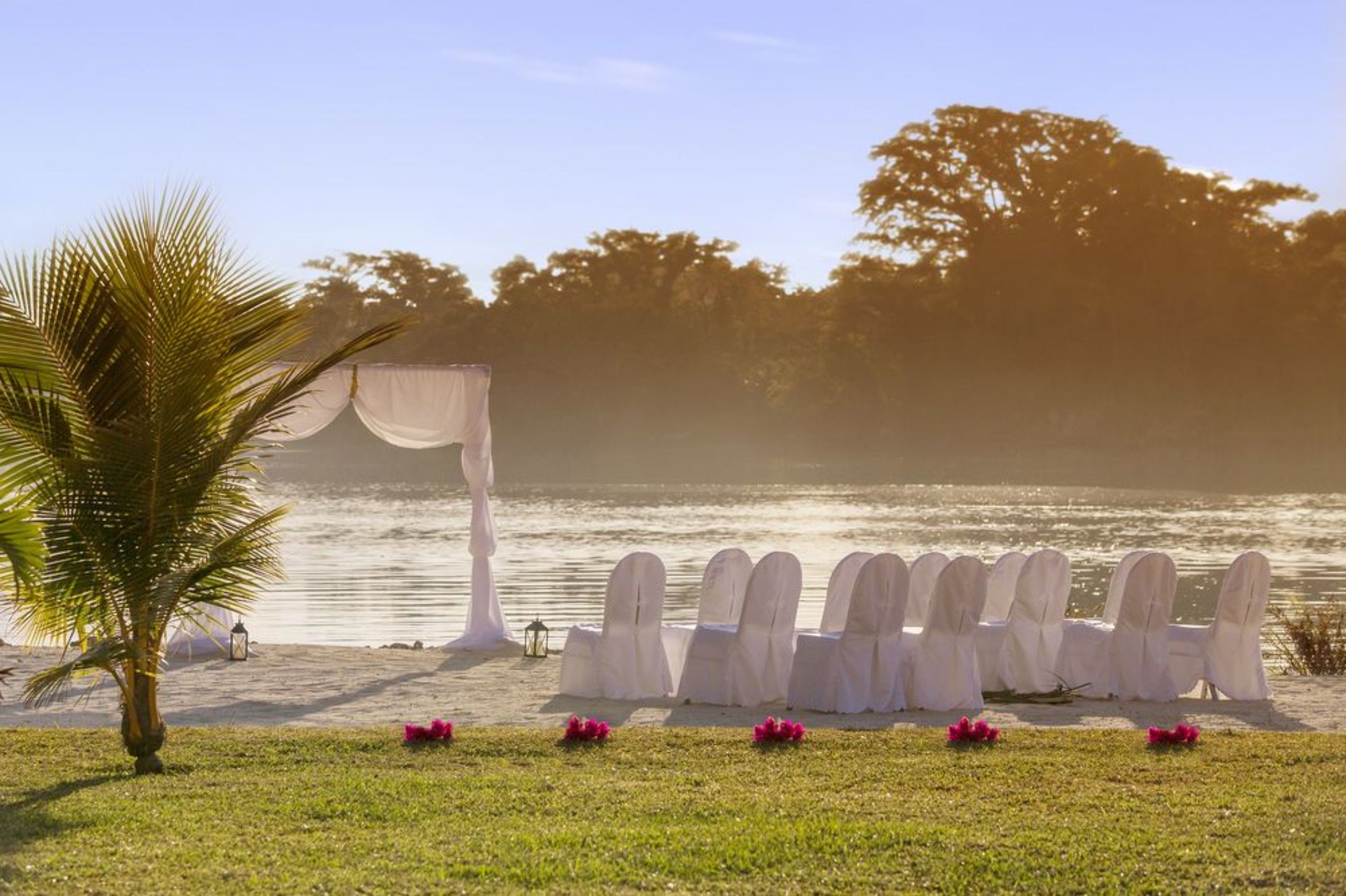 A beach wedding setup with a canopy and chairs arranged on the sand.