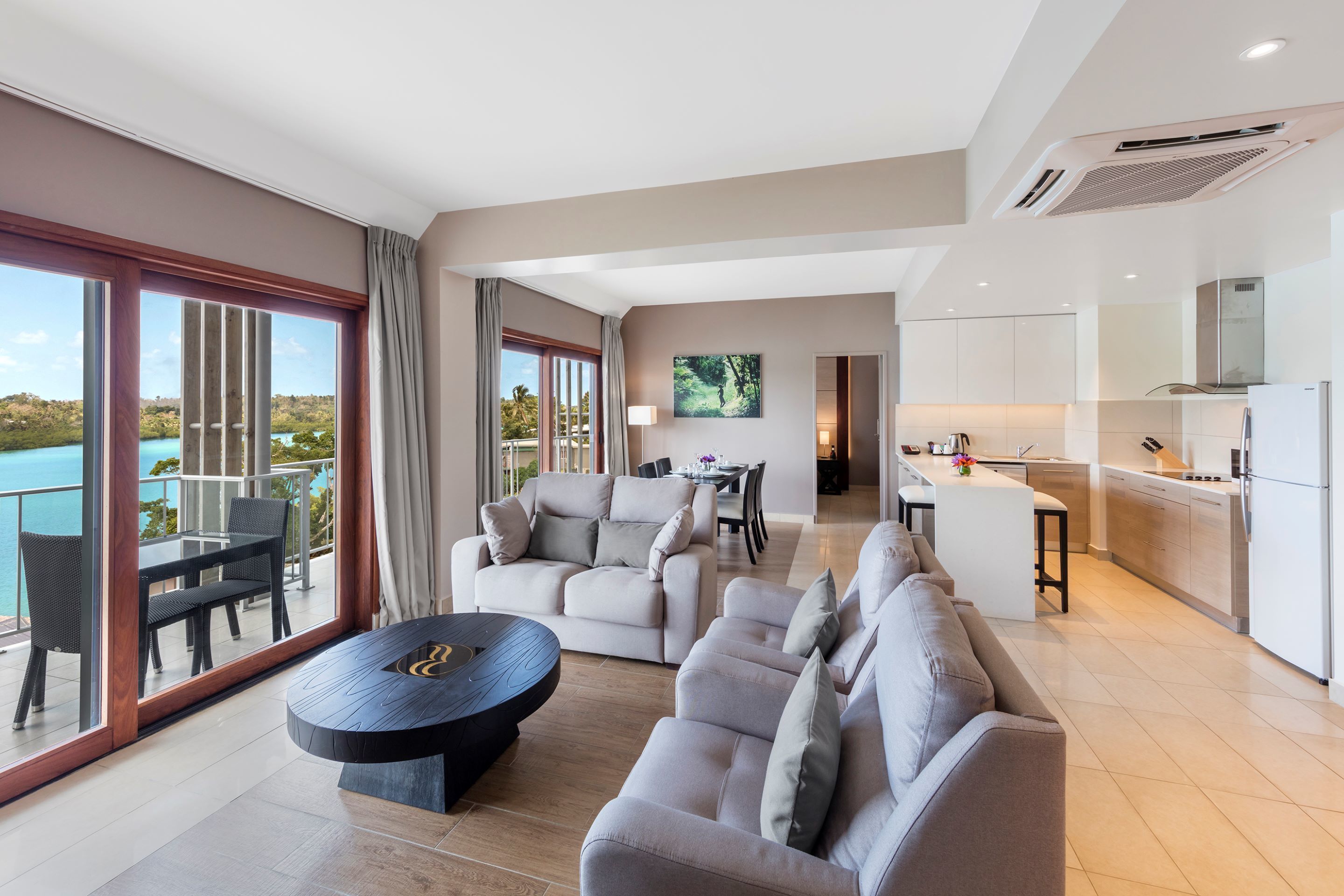 Una habitación de hotel moderna con balcón, comedor y cocina.