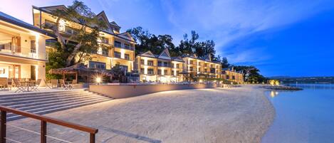 A beachfront hotel with multiple buildings, a sandy beach, and a calm sea.