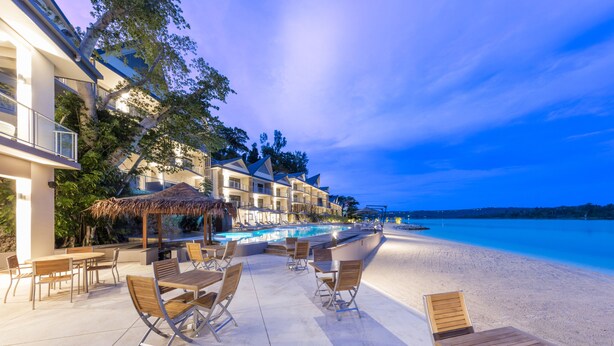Een hotel aan het strand met een zwembad, terras en uitzicht op de oceaan.