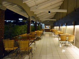 An indoor dining area with tables and chairs, a tiled floor, and a ceiling structure.