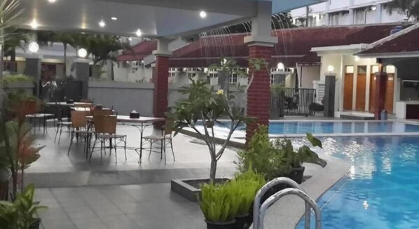 An indoor swimming pool area with a seating area and a small tree. - Ramayana Tasik (Tasikmalaya)
