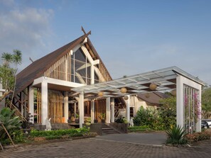 A modern building with a sloped roof, large windows, and a covered entrance area with potted plants. - Rumah Kito Jambi (Jambi)