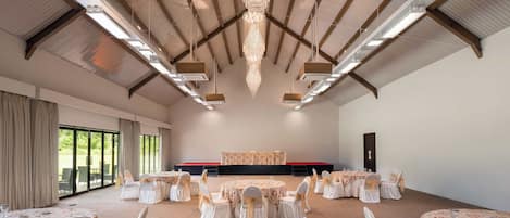 A large hall with high ceilings, chandeliers, and tables set for a formal event.