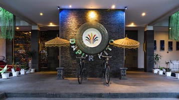 A reception area with a stone wall, two umbrellas, and a bicycle.