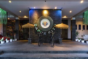 A reception area with a stone wall, two umbrellas, and a bicycle. - Rumah Kito Jambi (Jambi)