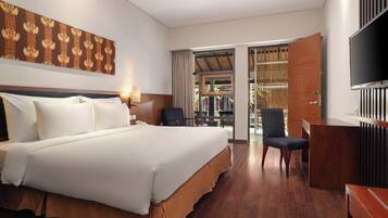 A hotel room with a large bed, a desk, a chair, a TV, and a view of the outdoors.