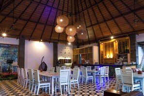 A restaurant interior with a high ceiling, hanging spherical light fixtures, a bar area, and a patterned floor. - Rumah Kito Jambi (Jambi)