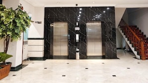 A lobby with a marble floor, two elevators, a staircase, and a potted plant. - Royal Asia Palembang (Palembang)