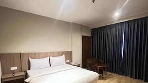 A modern hotel room with a large bed, a desk, and a chair. - Royal Asia Palembang (Palembang)