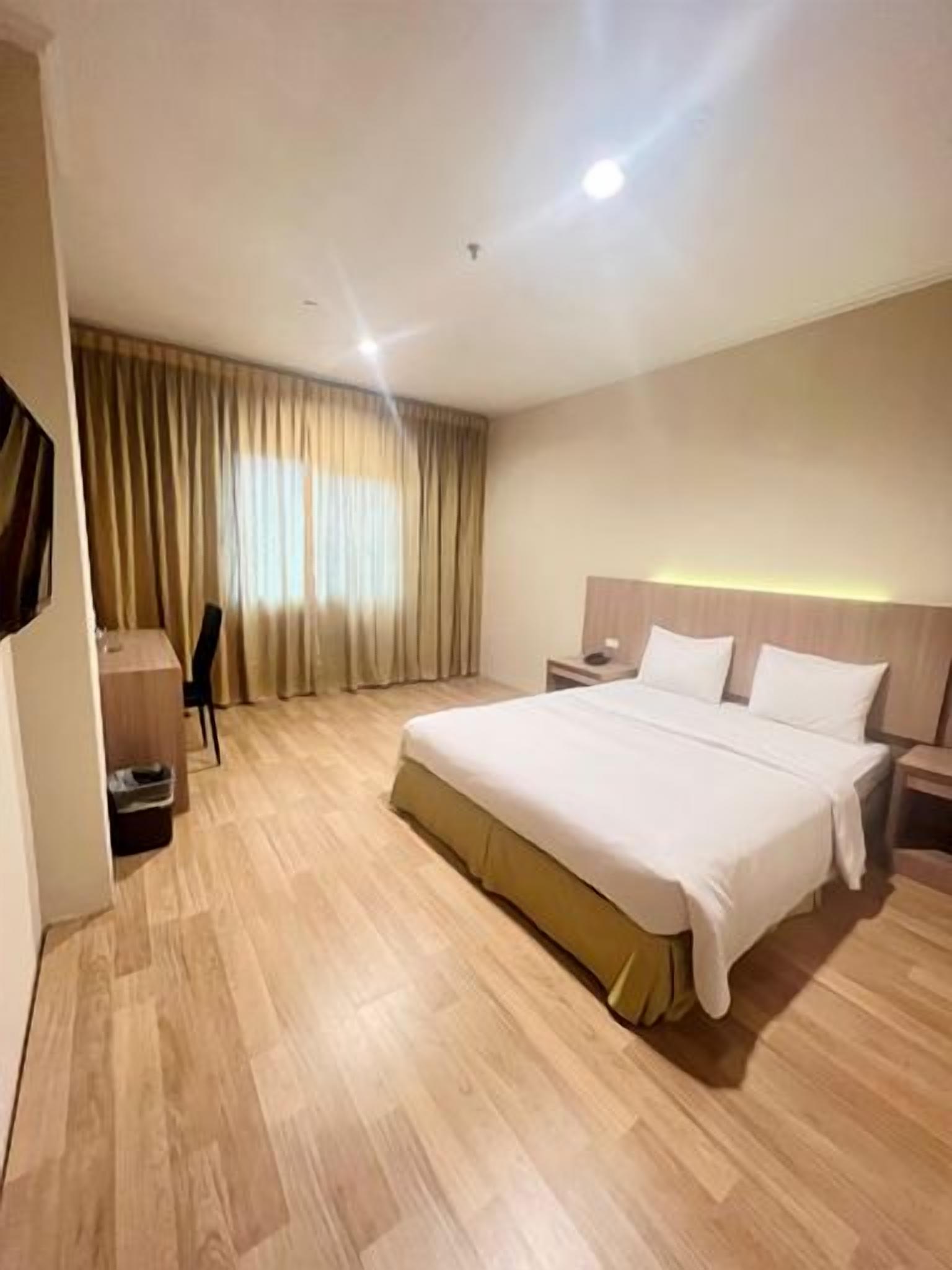 A hotel room with a large bed, bedside tables, a desk, and a chair.