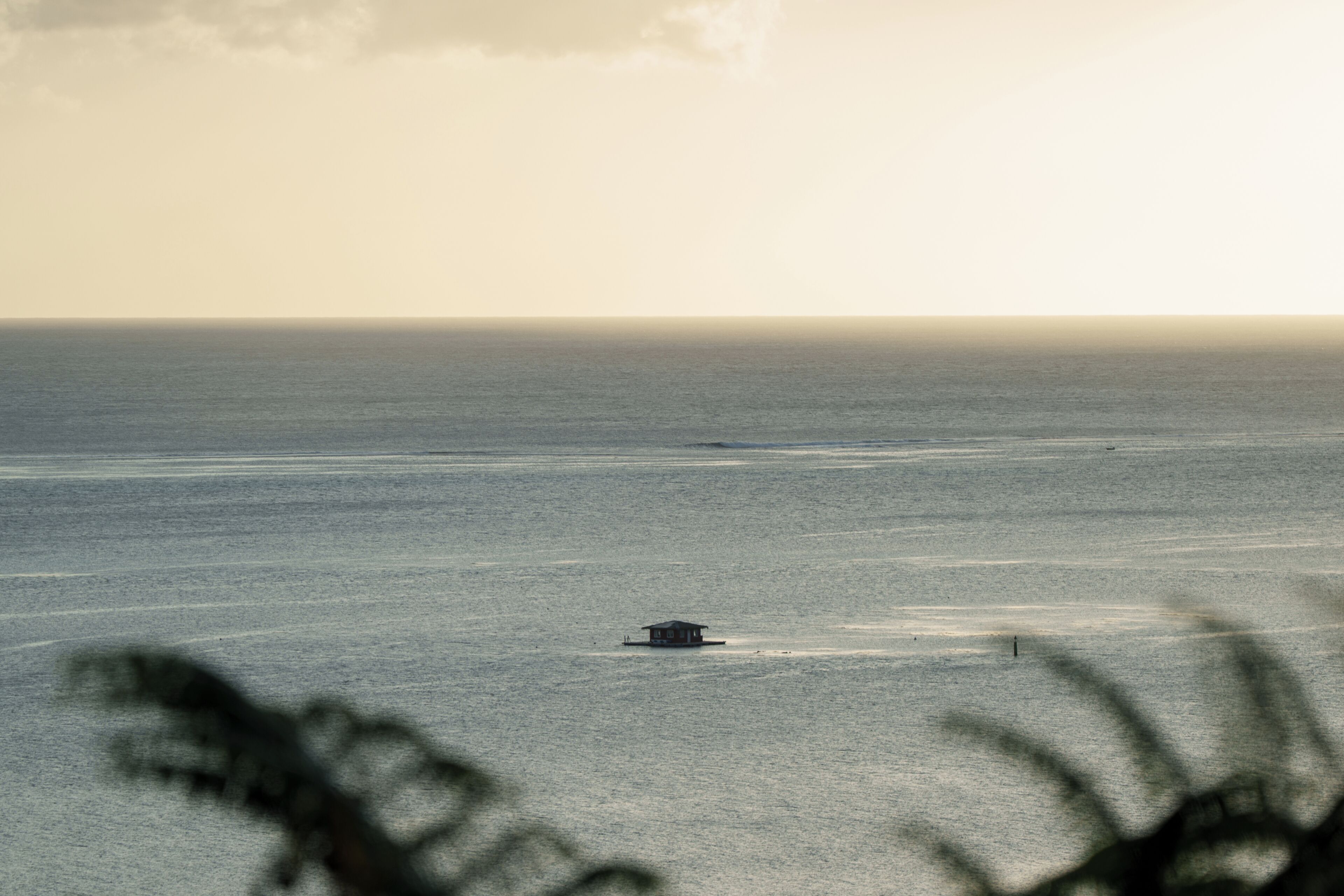 A solitary building on a calm sea with a clear horizon.