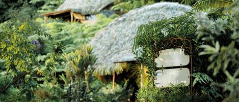 En bindingsværksbygning omgivet af frodig vegetation, med skilte der viser vejen til 'Reception' og 'Restaurant'.