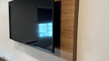 Un televisor de pantalla plana montado en una pared de madera, con un control remoto sobre una mesa de madera.